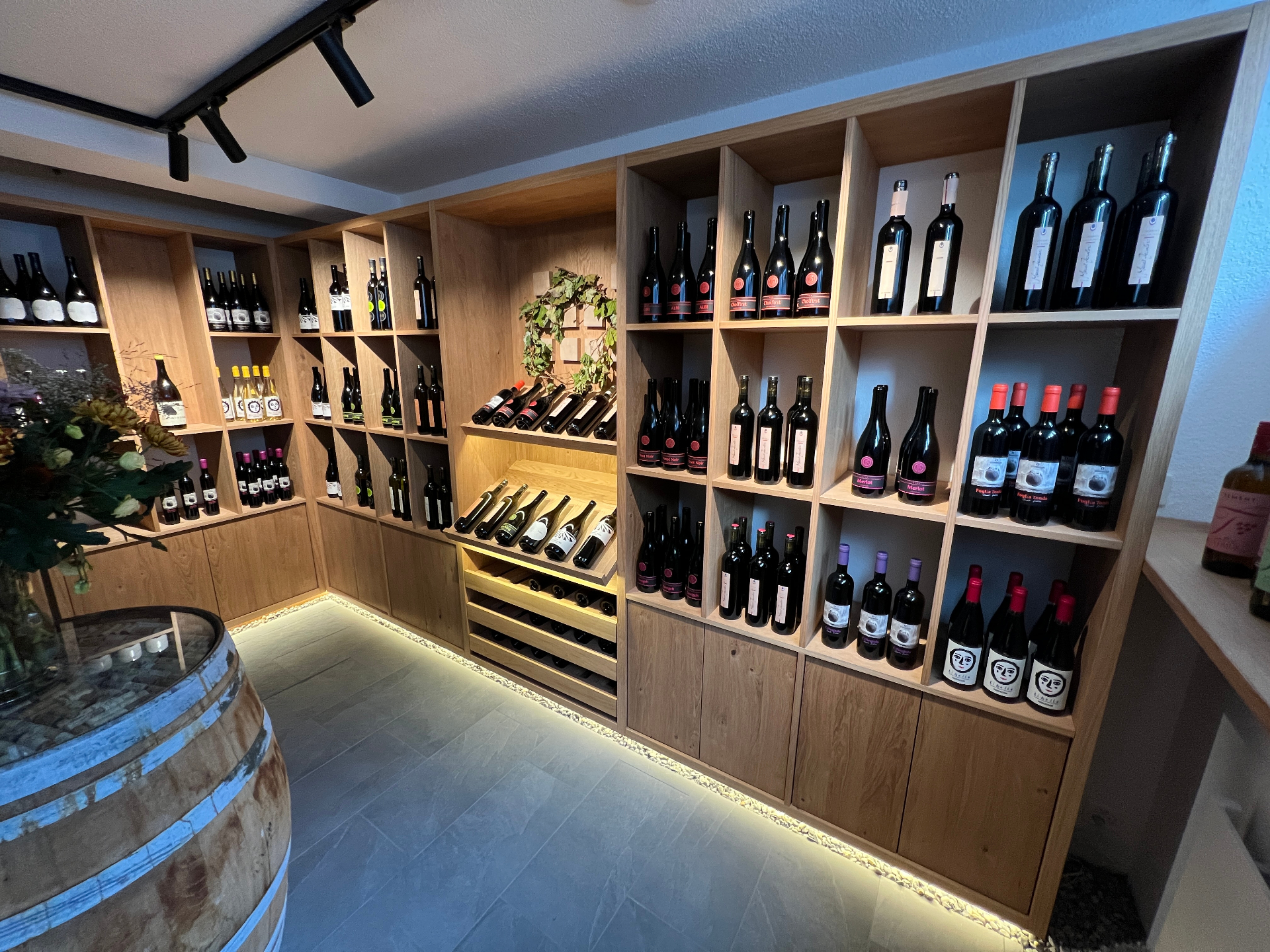 Innenraum des KernGrün Naturwein-Kellers in Richterswil mit Weinregalen aus Eiche und Holzfass